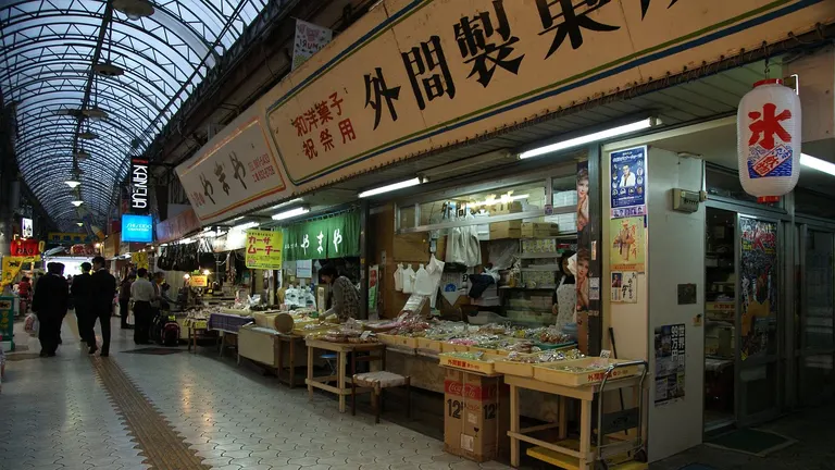 A colorful stall at a Japanese food market displaying fresh seafood and local produce.