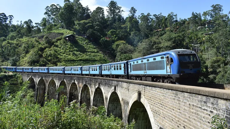Blue train traveling through green mountains in Sri Lanka hill country